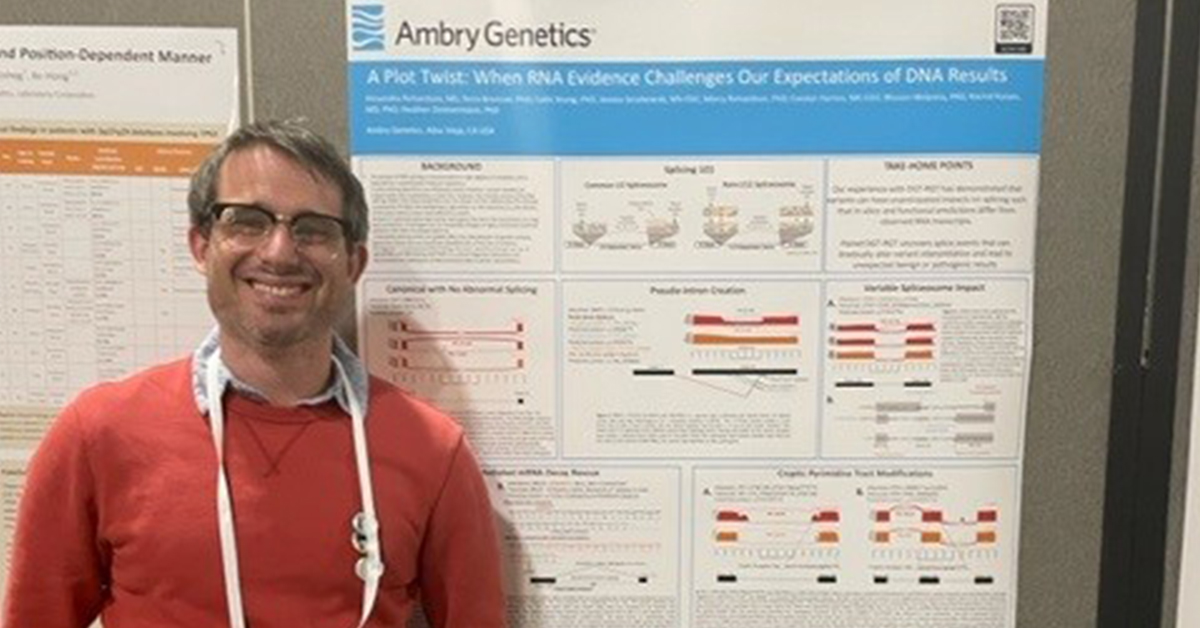 presenter stands next to his presentation poster at ACMG